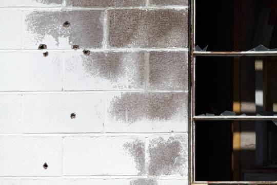 Damaged Brick Wall with Broken Window and Impact Marks Urban Decay Background