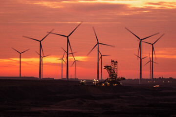 Obraz premium Open-pit coal mine excavator and windfarm during sunrise at Garzweiler, Germany