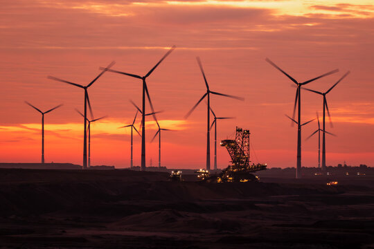 Open-pit coal mine excavator and windfarm during sunrise at Garzweiler, Germany