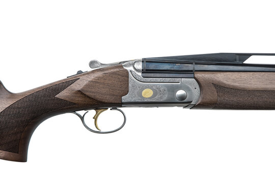 Side view close-up of an engraved shotgun receiver with golden trigger on a white back
