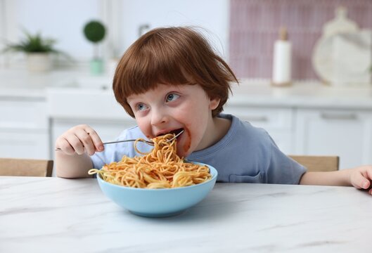 Little boy stained shirt while eating spaghetti at table indoors