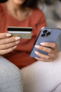 Close up hands holding mobile phone and credit card. Young female making secure online payments, enjoy remote shopping using financial technology and digital wallet app. E-commerce, cashless lifestyle