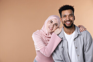 Fototapeta premium Portrait of happy muslim couple on beige background. Space for text