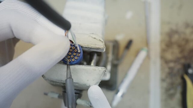 Professional in a sterile environment carefully uses precise soldering tools to assemble components in a cable production plant