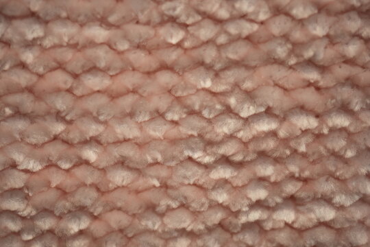macro texture of soft pink plush fabric. Close-up of cozy textile with delicate fibers and warm pastel tones. Smooth, soft surface creates a calm and comfortable background perfect for fashion, home d