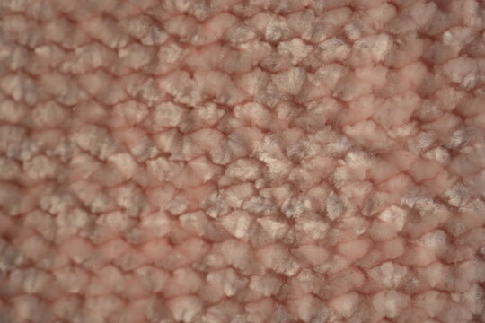 macro texture of soft pink plush fabric. Close-up of cozy textile with delicate fibers and warm pastel tones. Smooth, soft surface creates a calm and comfortable background perfect for fashion, home d