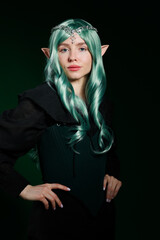 Obraz premium Beautiful girl dressed as elf on dark green background