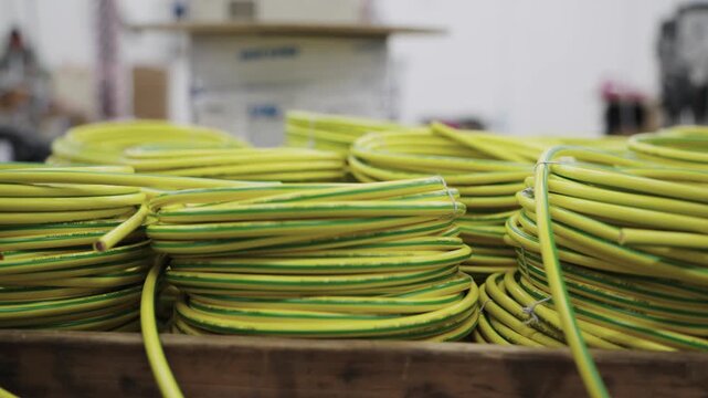 Batch of neatly coiled yellow and green cables displayed in an industrial setting, showcasing organization and efficient production processes