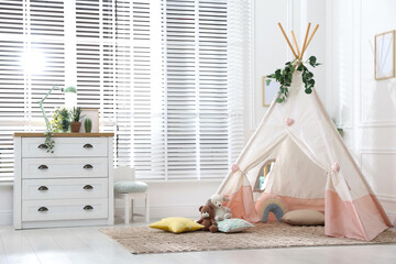 Toy wigwam with pillows, furniture and floral decor in room © New Africa