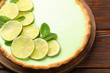 Tasty lime pie with fruit slices and mint leaves on wooden table, closeup © New Africa