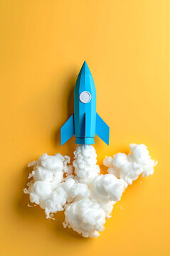 Cohete de cartulina azul con humo de algod&oacute;n sobre fondo amarillo, ideas, emprendimiento, innovaci&oacute;n, startups marketing, tecnolog&iacute;a, crecimiento, imaginaci&oacute;n y exito en desarrollo de proyectos