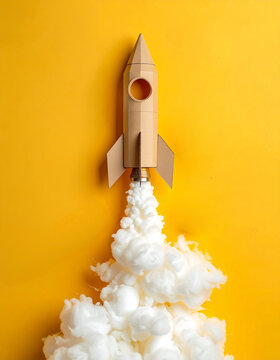 Cohete de cartulina con humo de algod&oacute;n sobre fondo amarillo, ideas, emprendimiento, innovaci&oacute;n, startups marketing, tecnolog&iacute;a, crecimiento, imaginaci&oacute;n y exito en desarrollo de proyectos