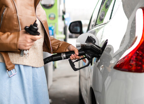 Woman Filling Up A Car At A Gas Station Holding A Fuel Nozzle
