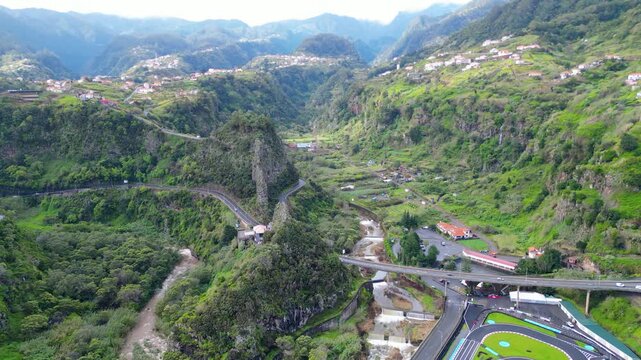 Dramatic aerial view of Madeira's verdant valleys and winding mountain roads, showcasing the island's unique landscape and charming hillside communities. Faial