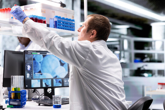 Researcher in clinical laboratory prepares solution with pipette and jars, mixing matter for genetics research and molecular analysis in biotechnology. Conducting advanced research study.