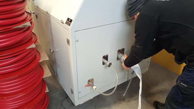  A 2.5-inch fire hose is being tested by attaching it to a fitting in a tank filled with water.