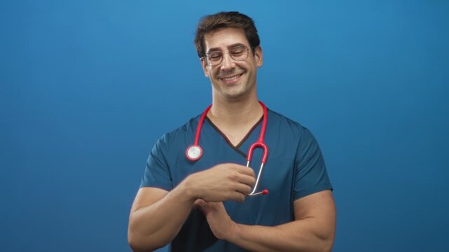 Man doctor points finger upward with red stethoscope and visible forearm, smiling in a blue studio backdrop; confidence care.