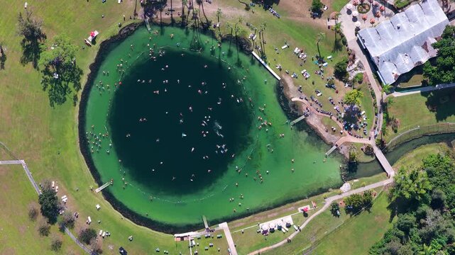 People relaxing in natural mineral spring lagoon in North Port, Florida, known for warm therapeutic water, wellness tourism, outdoor recreation and tropical scenery.