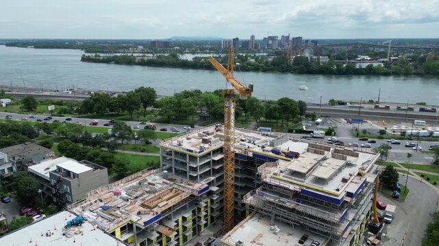 4K aerial drone flying past construction crane toward Jacques Cartier Bridge over St Lawrence River in Montreal