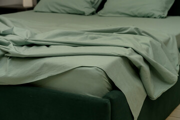 Soft green bedding on modern bed with rumpled sheets and pillows © bo.kvk