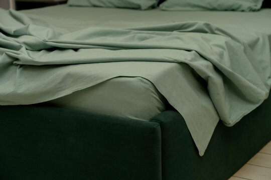 Green bedding set on modern bed with soft pillows and textured fabric