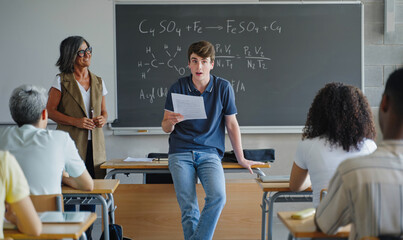 High school male student presenting his science project to classmates and teacher