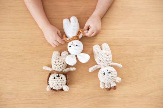 Little girl with toys at wooden table, top view