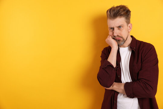 Resentful man on yellow background. Space for text
