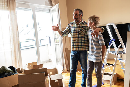 A father and son are unpacking boxes and moving into their new home.