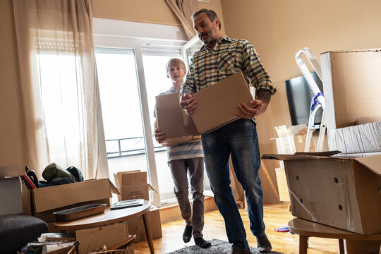 A father and son are unpacking boxes and moving into their new home.