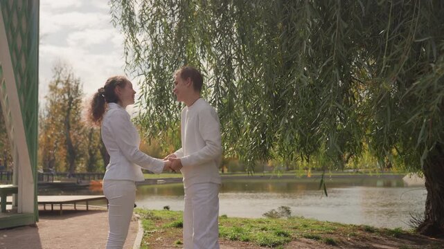 Two lovers exchange affectionate looks under warm sunlight at tranquil waterside. Pair shares intimate moments peacefully by serene lake with gentle sunlight illuminating their connection