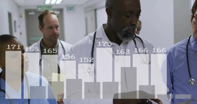 During patient rounds senior doctor leading team scrolling graphics on tablet walking hospital hall