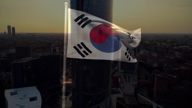 Steady breeze sending Taegukgi unfurling, billowing, flipping, revealing sunset city skyline