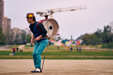 Obraz premium Latin American man posing with a bass drum on his back, dancing and spinning, Chilean chinchinero, street musician who plays the bass drum and cymbals and dances in the streets, Chilean cultural.