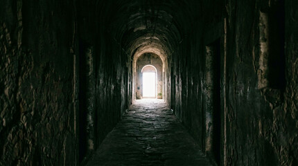 Obraz premium Ancient Stone Corridor With Light-Filled Archway At The End Of Dark Tunnel