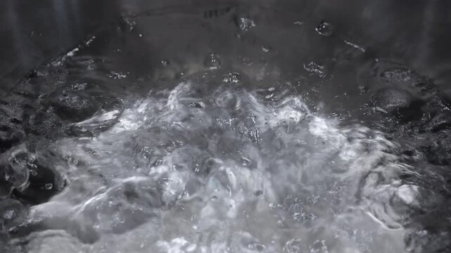 Boiling water in a stainless steel pot in slow motion