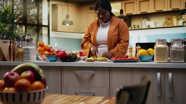 African american woman cutting cherry tomatoes to spread on avocado toast, filming a food vlog of culinary recipe tutorial for healthy eating. Sharing a breakfast idea on video.