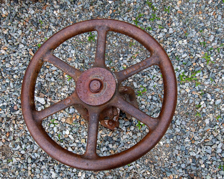 Rusty wheel on gravel outdoors