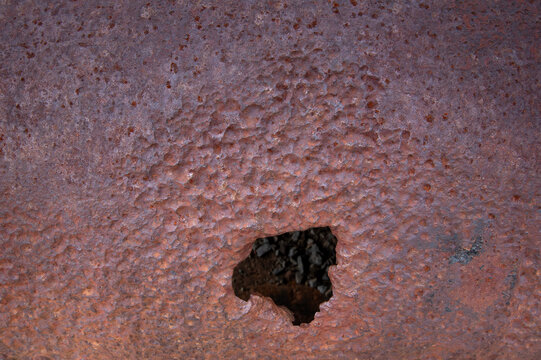 Rusty metal with a hole showing texture and color