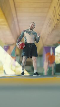 Tattooed football player showing thumbs up under a bridge