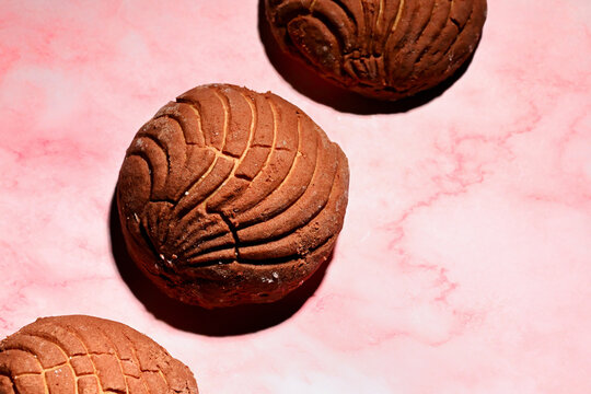 Chocolate concha sweet bread on pink background, color blocking style