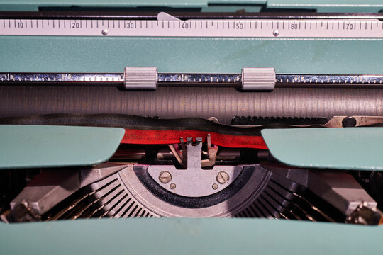 Close-up of typewriter typebars with letters and the black and red ink ribbon in focus