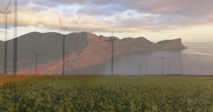 Sunlight breaking clouds causing ridge glow while turbines slowly rotating, revealing canola field