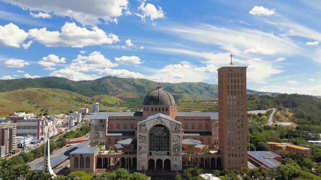 Aerial frontal view of National Shrine basilica facade with dome, tower and religious murals approaching toward entrance in Aparecida, Brazil. Approach camera movement