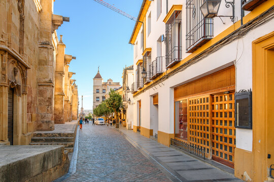 A narrow cobblestone street outside the outer wall of the Mezquita-Catedral of Cordoba leading to the 18th century Triumph of Saint Raphael monument in Cordoba, Spain.