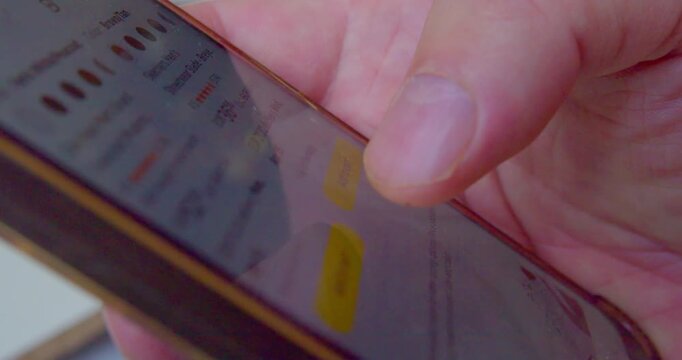 Macro shot of a finger pressing smartphone screen to select sneakers from an online store.