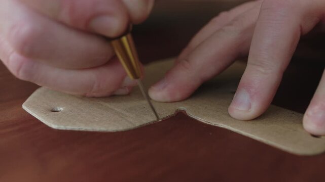 Leatherworker tracing a template with an awl