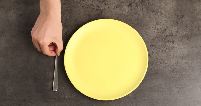 People with plate and cutlery at grey table, top view