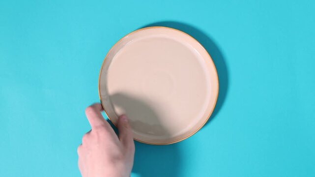 Man changing plates on light blue background, top view