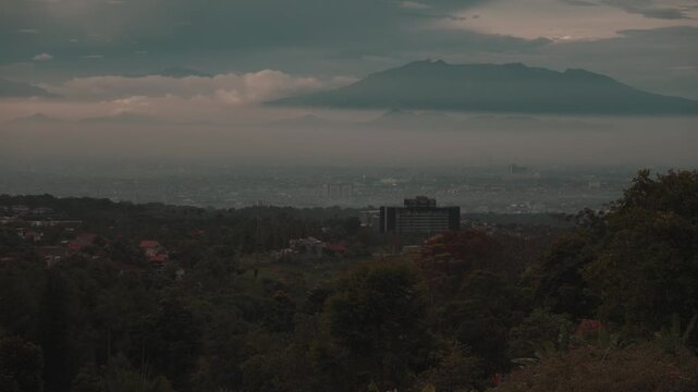 Cinematic misty forest mountain landscape during early morning with soft fog covering the valley. Filmed at Tebing Keraton, Bandung, West Java, Indonesia. Peaceful tropical scenery with lush greenery 